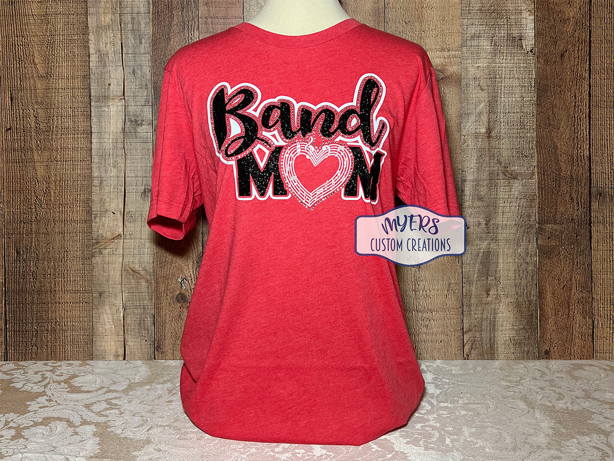 Band Mom with a heart-shaped music staff heather red Bella Canvas t-shirt with white and black glitter HTV and crystal rhinestones