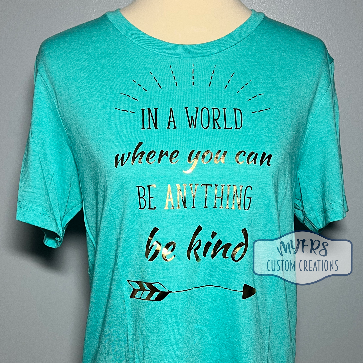 In a World Where You Can Be Anything Be Kind heather sea green Bella+Canvas t-shirt