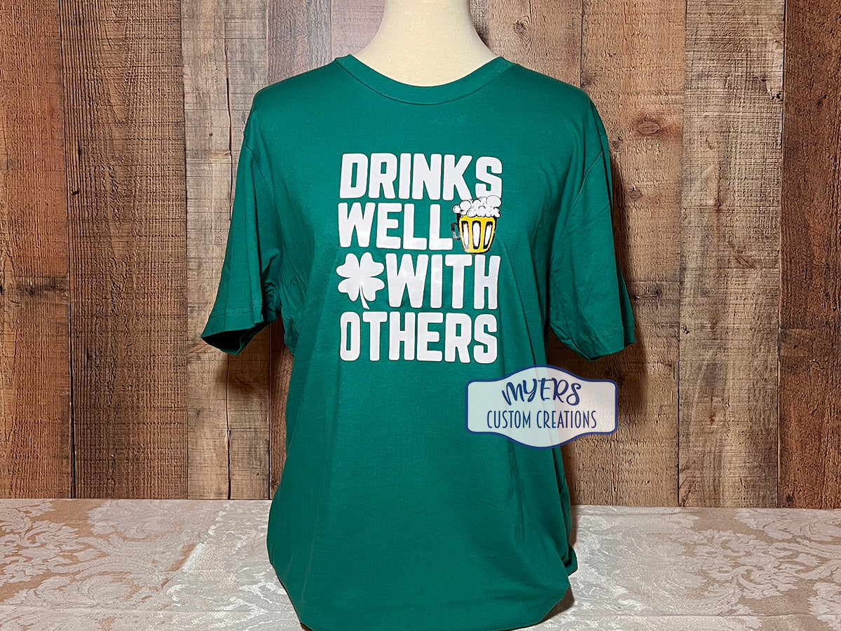 Drinks Well With Others St. Patrick's Day kelly green Bella+Canvas t-shirt with white, yellow, and black HTV RTS