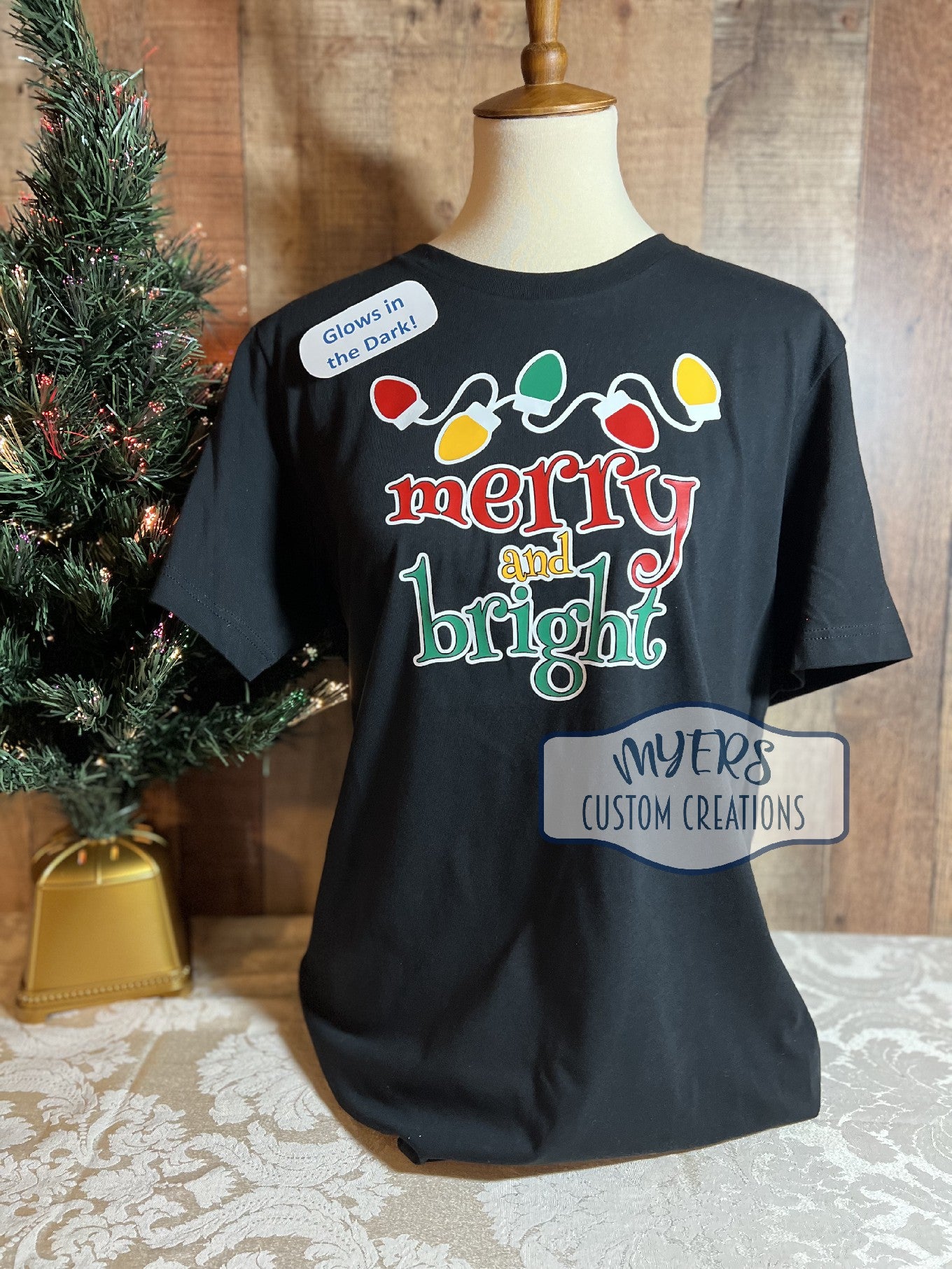 Merry and Brights Christmas Lights black t-shirt with glow in the dark white, red, green, & yellow HTV. Shown in the light.