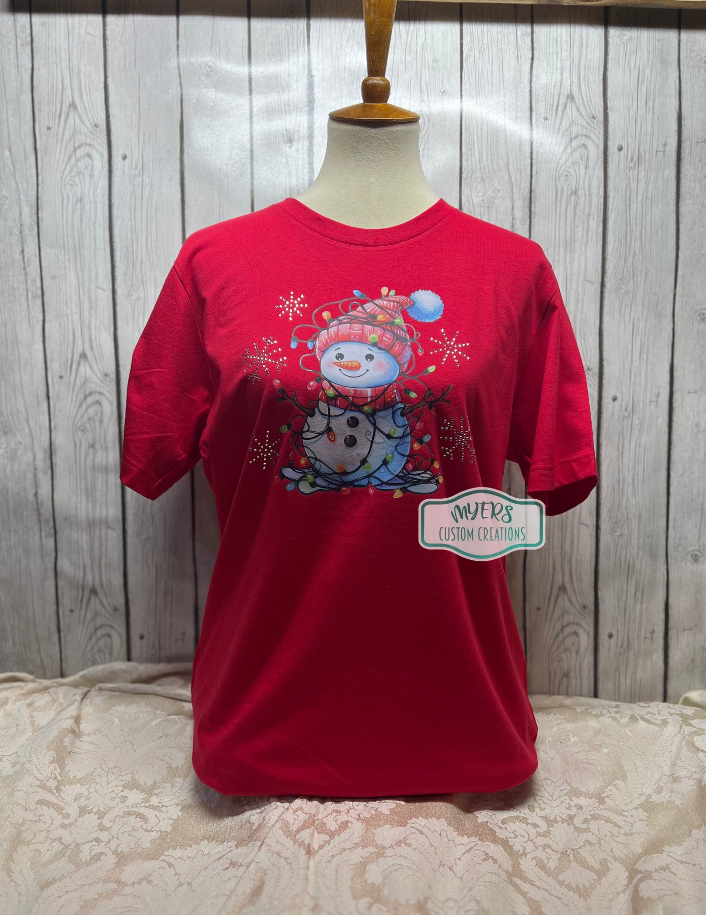 Snowman with Christmas Lights and crystal rhinestone snowflakes on a red Bella+Canvas t-shirt