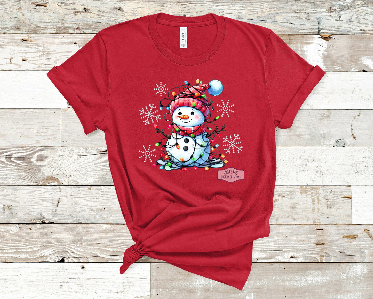 Snowman with Christmas Lights and crystal rhinestone snowflakes on a red Bella+Canvas t-shirt